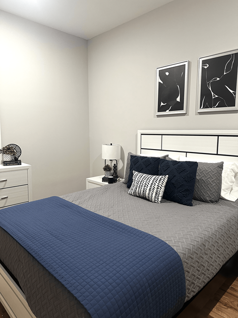 A bed with a blue comforter and pillows in a white room.